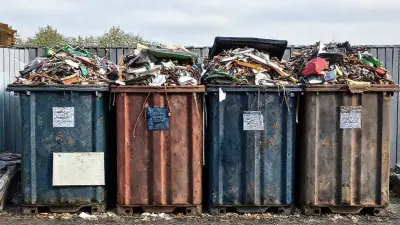 Four garbage containers filled to the brim and overflowing with scraps;