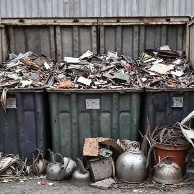 Four garbage containers filled to the brim with scraps overflowing from them; iron, steel teapots and metal scraps are visible in the picture taken from a different angle.