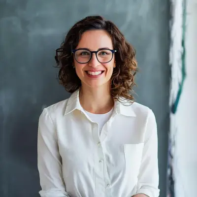 a teacher in white clothes, wearing glasses, smiling and looking at the camera