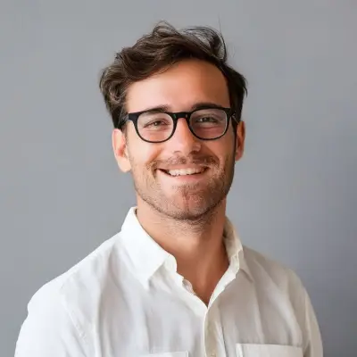 a male teacher in white clothes, wearing glasses, smiling and looking at the camera